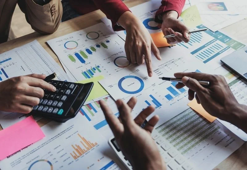 a group of business people sitting around a table with papers and calculators